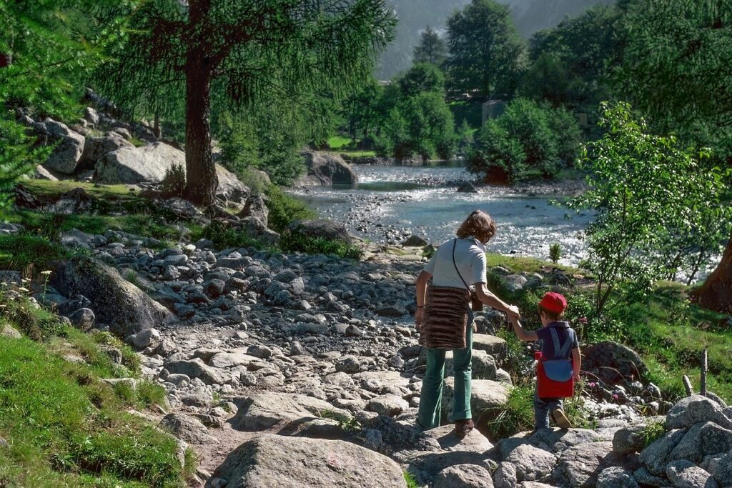 Foto, das eine Frau und ein Kind zeigt, die zusammen eine Wanderung an einem Fluss machen